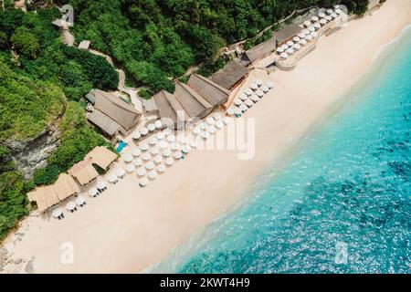 Luftblick auf den blauen Ozean und den Luxusstrand mit Sonnenschirmen auf Bali Stockfoto