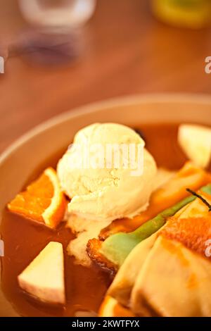 Crepes mit Vanilleeis, Orangensoße und frischen Orangen Stockfoto