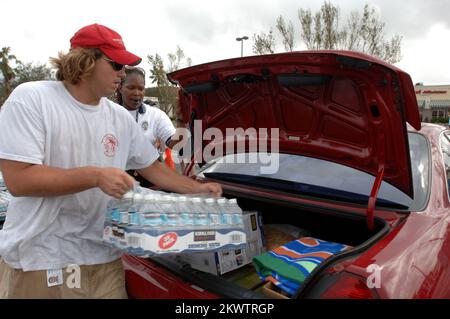 Hurricane Wilma, Hollywood, FL, 1. November 2005 Volunteer William White, Rettungsschwimmer des Driftwood Community Pool, lädt Eis und Wasser in einem Auslieferungszentrum am Oakwood Plaza für Einwohner, die vom Hurrikan Wilma betroffen sind. Polizist Beverly Perez hilft auch. Fotos zu Katastrophen- und Notfallmanagementprogrammen, Aktivitäten und Beamten Stockfoto