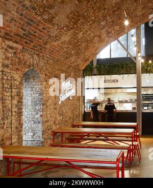 Sitzplätze in Bahnbögen. Camden Town Beer Hall, London, Großbritannien. Architekt: Gundry & Ducker, 2021. Stockfoto