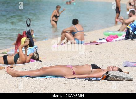 04.09.2016., Primosten, Kroatien - der Sommer ist vorbei und verkündete das schlechtere Wetter. Am Primosten Beach gibt es immer noch Gäste, die gerne schwimmen und sich sonnen, während einige Bücher oder Zeitungen lesen Stockfoto