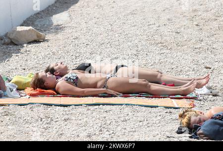 04.09.2016., Primosten, Kroatien - der Sommer ist vorbei und verkündete das schlechtere Wetter. Am Primosten Beach gibt es immer noch Gäste, die gerne schwimmen und sich sonnen, während einige Bücher oder Zeitungen lesen Stockfoto