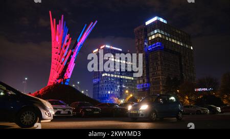 Anti-Kommunismus-Kampfdenkmal Wings, zwei gläserne Bürogebäude bei Nacht, geparkte Autos. Bukarest, Rumänien - 30. Oktober 2022. Stockfoto