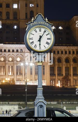 Öffentliche Uhr im Parlamentspalast in Bukarest, Rumänien, teilweise beleuchtet bei Nacht, um Energiekosten zu senken. Vertikal. Stockfoto