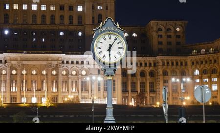 Öffentliche Uhr im Parlamentspalast in Bukarest, Rumänien, teilweise beleuchtet bei Nacht, um Energiekosten zu senken. Stockfoto