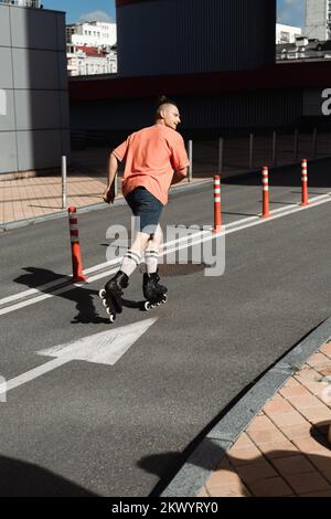 Seitenansicht eines Mannes in Rollschuhen, der auf der Straße in der Stadt Schlittschuh läuft, Stockbild Stockfoto