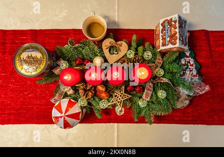 Vier brennende Kerzen auf einem schön dekorierten Adventskranz von oben nach unten. Stockfoto