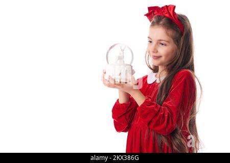 Lächelnde Frau mit weihnachtlicher Schneekugel mit Schneeflocken und Hirschen, Mädchen in rotem Weihnachtsmannkleid auf weißem Hintergrund Stockfoto