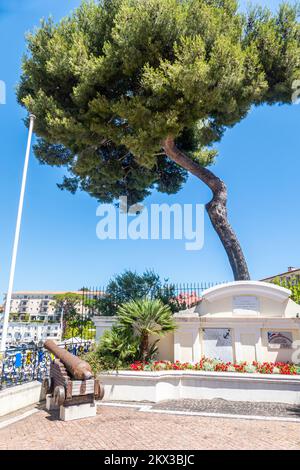 Saint Jean, Frankreich - 07/04/2021: Der Hauptplatz von Saint Jean Cap Ferrat mit einem Denkmal, einem Olivenbaum und antiken Kanonen Stockfoto