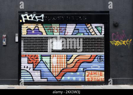 Graffiti und Straßenkunst auf Fensterläden in Shoreditch London Stockfoto