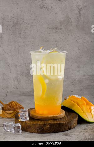 Boba- oder Tapiokapperlen ist taiwan Seifenmilchtee in Plastikbecher mit Mango-Zitronen-Aroma auf texturiertem Hintergrund, Sommererfrischung. Stockfoto