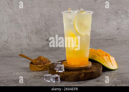 Boba- oder Tapiokapperlen ist taiwan Seifenmilchtee in Plastikbecher mit Mango-Zitronen-Aroma auf texturiertem Hintergrund, Sommererfrischung. Stockfoto