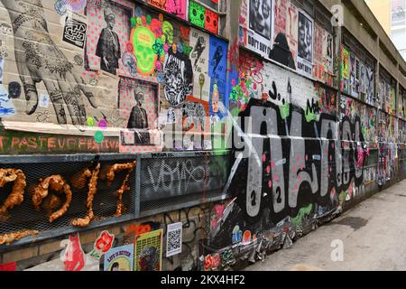 Poster, Paste-Ups, Graffiti und Straßenkunst an einer Wand in der Dereham Street, Shoreditch Stockfoto