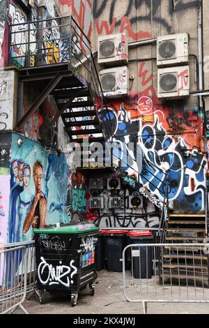 Eine Mischung aus Graffiti und Straßenkunst auf der Rückseite des Gebäudes mit Feuerleiter und Klimaanlage Shoreditch, London Stockfoto