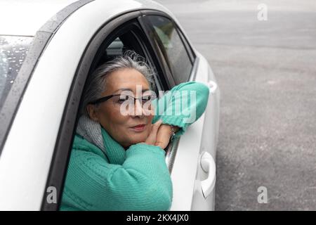 Eine Erwachsene Dame sitzt im Auto und schaut aus dem Fenster Stockfoto