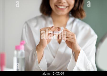 Eine unbekannte Frau im weißen Bademantel, die zu Hause Maniküre macht Stockfoto