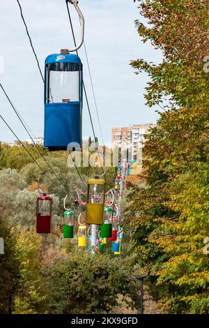 Farbenfrohe Kabinen im Vergnügungspark der Stadt Kharkiv mit bunten Bäumen Stockfoto