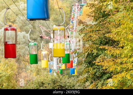 Farbenfrohe Seilbahn-Hütten im Vergnügungspark Kharkiv mit bunten Bäumen Stockfoto