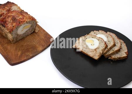 Rumänisches Festtagsgericht namens Drob, gebackenes Lamm oder Schweinefleisch und Leber, mit Zwiebeln Petersilie Knoblauch und gekochten Eiern in der Mitte. Isoliert auf Whit Stockfoto