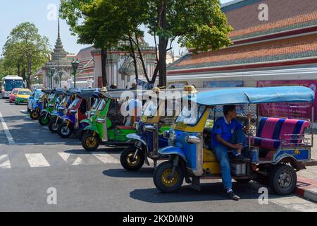 Bangkok, Thailand - März 19. 2018: Eine Auto-Rikscha, die in seinem Fahrzeug vor einer Reihe Tuk Tuks auf Kunden wartet. Stockfoto