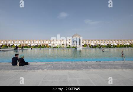 Ein muslimisches Paar sitzt vor der Schah-Moschee auf dem Naghsh e Jahan Square oder Imam Square. Isfahan, Iran Stockfoto