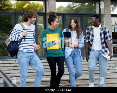 Eine Gruppe unterschiedlicher Studenten, die miteinander reden und auf dem Campus spazieren gehen Stockfoto