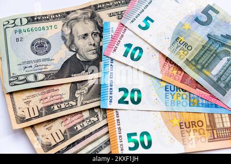 Nahaufnahme von US-Dollar-Scheinen und Euro-Banknoten, isoliert auf weißem Hintergrund. Stockfoto