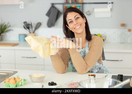 Eine Frau, die eine Pizza zubereitet, hält das Gebäck in ihren Händen Stockfoto