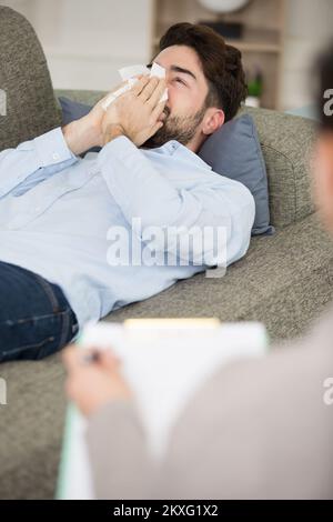Psychologe, der einem traurigen Mann auf dem Sofa zuhört Stockfoto