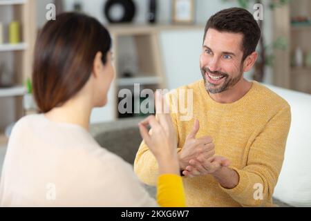 Fröhliches Paar kommuniziert mit Gebärdensprache Stockfoto