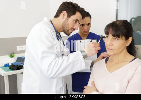 Aufmerksamer Arzt, der die Ohruntersuchung der Frau durchführt Stockfoto