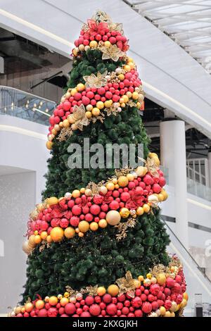 Weihnachtsbaum im großen Einkaufszentrum. Frohe Neujahrsferien. Dekoration und Lichter. Weihnachtsdekoration Glaskoffer. Stockfoto