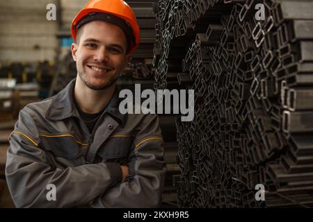 Porträt eines fröhlichen Arbeiters, der auf einem Metallstock posiert Stockfoto