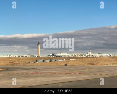 Internationaler Flughafen Denver, Colorado, USA - 24. November 2022: Blick auf den Kontrollturm und das Jeppesen Terminal von der Landebahn unter einem wolkigen Himmel. Stockfoto