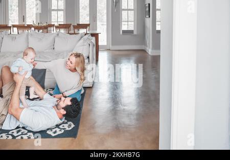 Glücklich, Liebe und Familie spielen im Wohnzimmer zusammen, während sie entspannen, sich verbinden und Spaß haben. Glück, Fürsorge und Eltern mit ihrem Baby auf dem Stockfoto