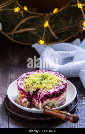 Gekleideter Hering, weihnachtliche sowjetische Salate aus Hering und Gemüse in einer Neujahrsdekoration. Stockfoto