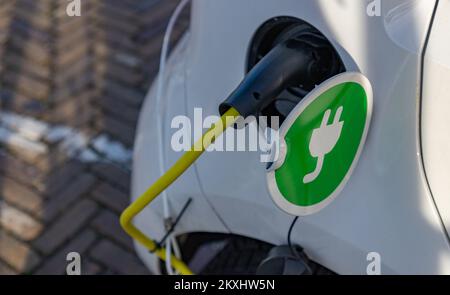 Ein Bild eines kleinen Elektroautos, das auf der Straße aufgeladen wird. Stockfoto