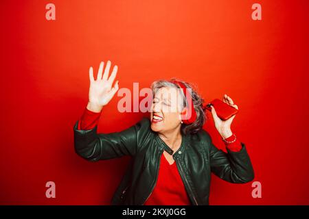 Ältere Frau in roter Kleidung, auf rotem Hintergrund Stockfoto