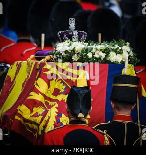 Der Sarg ist geschmückt mit dem Königlichen Standard , der Imperial State Crown und Septre , die während der feierlichen Prozession fotografiert wurden , um den Sarg ihrer verstorbenen Majestät Königin Elizabeth II . vom Buckingham-Palast zum Palace of Westminster in der Mall in London am Mittwoch , dem 14 . September 2022 , zu transportieren . Bild von Julie Edwards. Stockfoto