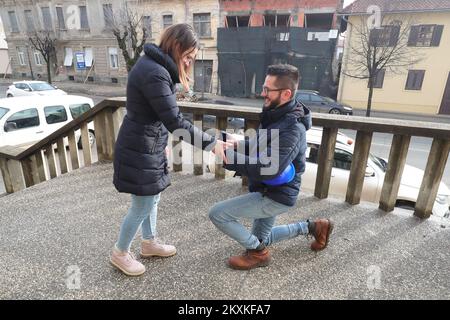 Dekan Jadanic machte seiner Freundin Ana Krznarevic am 9. Januar 2021 in den Ruinen einen Heiratsantrag vor dem Gesundheitszentrum in Petrinja, Kroatien. Sie trafen sich vor vier Jahren im Laden, wo sie arbeitete, an ihrem Geburtstag. Sie haben ein paar Monate später eine Beziehung begonnen und sind seitdem unzertrennlich. Dean arbeitet seit dreizehn Jahren als Medizintechniker am Petrinja Health Center, und nach dem letzten Erdbeben am 29. Dezember zog er sich kaum den Kopf raus. Jetzt helfen beide freiwillig den Opfern des Erdbebens, so dass sie selten einen sehen Stockfoto