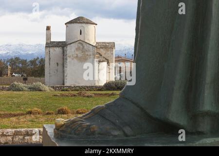 Die Bilder zeigen den Fuß des Denkmals für St. Gregory von Nin mit Blick auf die Kirche des Heiligen Kreuzes, die als kleinste Kathedrale der Welt bezeichnet wird, ist das wertvollste erhaltene Denkmal der alten kroatischen Kirchenarchitektur und eines der Symbole von Nin., in Nin, Kroatien, am 15. März 2021. Foto: Marko Dimic/PIXSELL Stockfoto