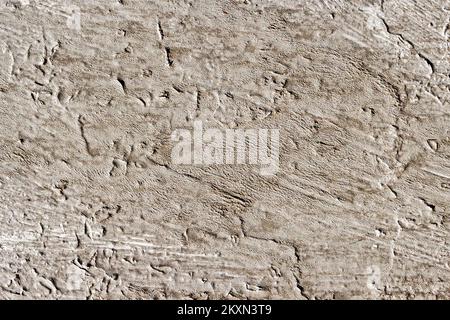 Abstrakter Hintergrund einer alten graubraunen Betonwand mit gerillter, zerkratzter Textur Stockfoto