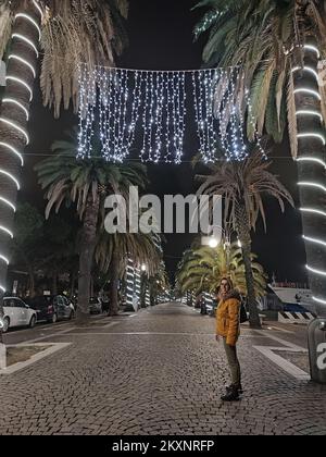 Süßer romantischer Spaziergang entlang der Küste am Hafen in einer maritimen Stadt an einem Weihnachtsabend zwischen Lichtern und Dekorationen in der toskana Stockfoto