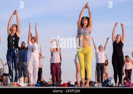 Die Menschen üben Yoga, während die Sonne untergeht am Gruß zur Sonne Monument im Rahmen der Feier des Inernational Yoga Day in Zadar, Kroatien am 17. Juni 2021. Das Denkmal wurde vom kroatischen Architekten Nikola Basic entworfen und symbolisiert die Kommunikation mit der Natur und kommuniziert mit Licht. Foto: Dino Stanin/PIXSELL Stockfoto