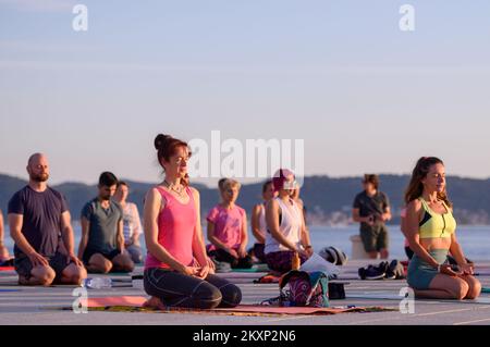 Die Menschen üben Yoga, während die Sonne untergeht am Gruß zur Sonne Monument im Rahmen der Feier des Inernational Yoga Day in Zadar, Kroatien am 17. Juni 2021. Das Denkmal wurde vom kroatischen Architekten Nikola Basic entworfen und symbolisiert die Kommunikation mit der Natur und kommuniziert mit Licht. Foto: Dino Stanin/PIXSELL Stockfoto