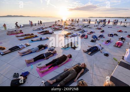 Die Menschen üben Yoga, während die Sonne untergeht am Gruß zur Sonne Monument im Rahmen der Feier des Inernational Yoga Day in Zadar, Kroatien am 17. Juni 2021. Das Denkmal wurde vom kroatischen Architekten Nikola Basic entworfen und symbolisiert die Kommunikation mit der Natur und kommuniziert mit Licht. Foto: Dino Stanin/PIXSELL Stockfoto