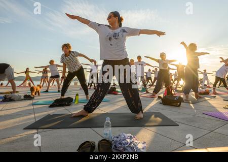 Die Menschen üben Yoga, während die Sonne untergeht am Gruß zur Sonne Monument im Rahmen der Feier des Inernational Yoga Day in Zadar, Kroatien am 17. Juni 2021. Das Denkmal wurde vom kroatischen Architekten Nikola Basic entworfen und symbolisiert die Kommunikation mit der Natur und kommuniziert mit Licht. Foto: Dino Stanin/PIXSELL Stockfoto