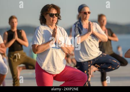 Die Menschen üben Yoga, während die Sonne untergeht am Gruß zur Sonne Monument im Rahmen der Feier des Inernational Yoga Day in Zadar, Kroatien am 17. Juni 2021. Das Denkmal wurde vom kroatischen Architekten Nikola Basic entworfen und symbolisiert die Kommunikation mit der Natur und kommuniziert mit Licht. Foto: Dino Stanin/PIXSELL Stockfoto