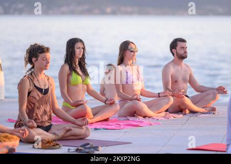 Die Menschen üben Yoga, während die Sonne untergeht am Gruß zur Sonne Monument im Rahmen der Feier des Inernational Yoga Day in Zadar, Kroatien am 17. Juni 2021. Das Denkmal wurde vom kroatischen Architekten Nikola Basic entworfen und symbolisiert die Kommunikation mit der Natur und kommuniziert mit Licht. Foto: Dino Stanin/PIXSELL Stockfoto