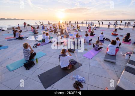 Die Menschen üben Yoga, während die Sonne untergeht am Gruß zur Sonne Monument im Rahmen der Feier des Inernational Yoga Day in Zadar, Kroatien am 17. Juni 2021. Das Denkmal wurde vom kroatischen Architekten Nikola Basic entworfen und symbolisiert die Kommunikation mit der Natur und kommuniziert mit Licht. Foto: Dino Stanin/PIXSELL Stockfoto